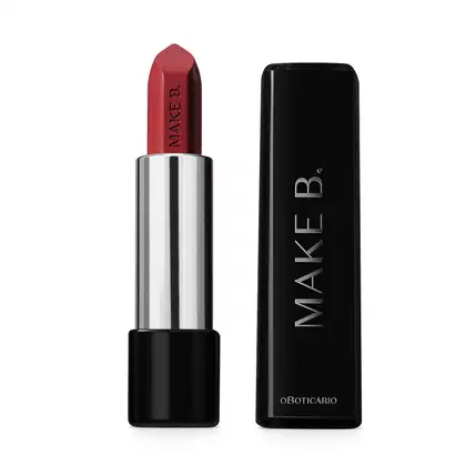 Batom em tom avermelhado da marca Make B. aberto. De um lado, a tampa preta com texto em branco, com formato retangular e ponta arredondada. Do outro, a base preta, o corpo prateado e a bala de batom aparente com a marca gravada em baixo relevo.