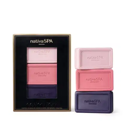 Caixa contendo três barras de sabonete Nativa SPA. Elas são de diferentes tons de rosa e roxo, com o nome da marca impresso em cada uma. A caixa tem um design elegante em preto e dourado. Ao lado, as mesmas barras são apresentadas fora da embalagem.