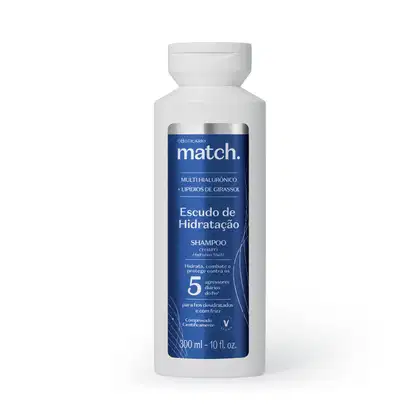 Frasco branco de item de perfumaria com rótulo azul e prata. Texto "match." e "Escudo de Hidratação" visível. Produto descrito como shampoo com multi-hialurônico e lipídios de girassol, para cabelos desidratados.