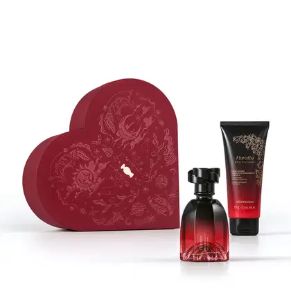 Caixa vermelha em formato de coração com relevo dourado de temática celestial. A frente, um frasco de item de perfumaria  Floratta Red Passion e bisnaga de creme corporal da mesma marca, ambos com embalagem degradê de vermelho para preto e tampa preta.