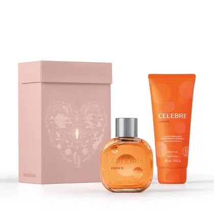 Caixa de presente de cor rosa claro com um grande coração contendo ilustrações em relevo de temática celestial. Ao lado, dois itens de perfumaria da linha Celebre agora na cor laranja, sendo um frasco de desodorante colônia e uma bisnaga de creme corporal
