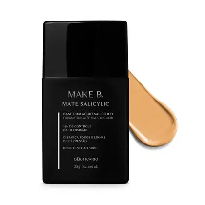 Frasco preto de base da linha Make B. Mate Salicylic com texto em branco trazendo informações do produto, como presença de ácido salicílico, controle de oleosidade e resistência ao suor. Atrás da embalagem, vemos um pouco de base bege clara espalhada.