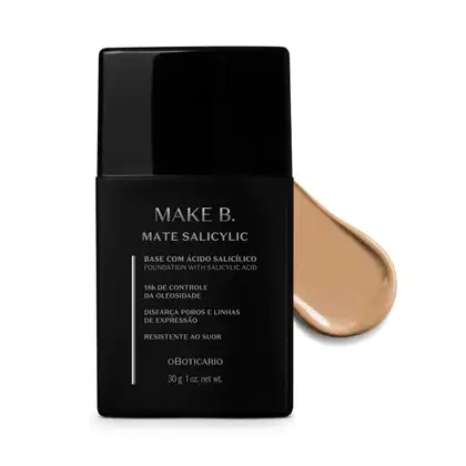 Frasco preto de base da linha Make B. Mate Salicylic com texto em branco trazendo informações do produto, como presença de ácido salicílico, controle de oleosidade e resistência ao suor. Atrás da embalagem, vemos um pouco de base bege clara espalhada.