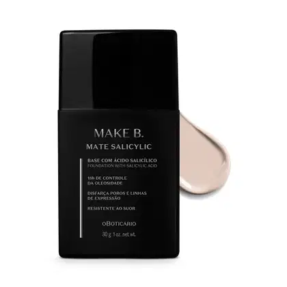Frasco preto de base da linha Make B. Mate Salicylic com texto em branco trazendo informações do produto, como presença de ácido salicílico, controle de oleosidade e resistência ao suor. Atrás da embalagem, vemos um pouco de base branca espalhada.