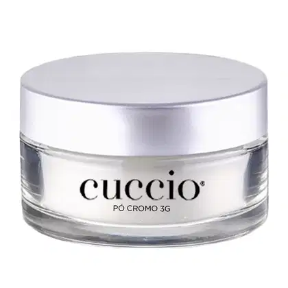O produto apresentado é um pó cromo 3G da marca Cuccio. A embalagem é um recipiente circular de vidro transparente com uma tampa prateada. O rótulo do produto exibe claramente o nome "Cuccio" em letras pretas.