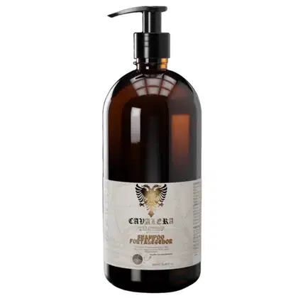 Frasco de shampoo da marca Cavalera, com embalagem de vidro escuro e rótulo branco com brasão dourado. Possui bomba de acionamento preta na parte superior.