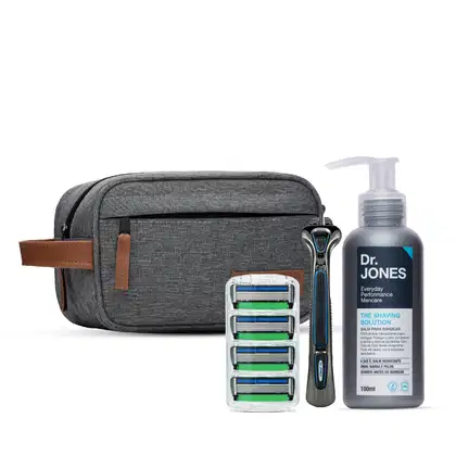 O conjunto inclui um estojo de viagem cinza, um barbeador, cartuchos de lâminas de barbear e um frasco de 100ml da Solução de Barbear da Dr. Jones, com design moderno e minimalista.