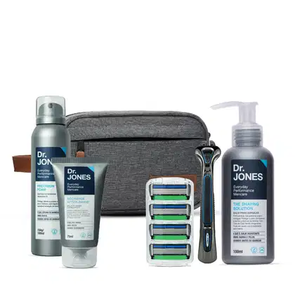 Conjunto de produtos de cuidados pessoais da marca Dr. Jones, incluindo espuma de barbear, bálsamo pós-barba, solução de barbear e lâminas de barbear em embalagens de plástico e tecido cinza.
