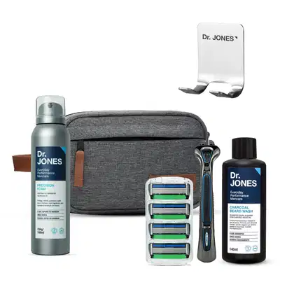 Conjunto de produtos de cuidados pessoais da marca Dr. Jones, incluindo espuma de barbear, shampoo para barba, barbeador e estojo de transporte em tons de cinza e azul.