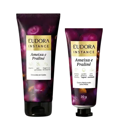 Dois produtos da marca Eudora Instance: um creme perfumado para mãos em embalagem de 30g e um sabonete em barra de 180ml, ambos com rótulos em fundo roxo e detalhes em dourado, apresentando a fragrância "Ameixa e Praline".