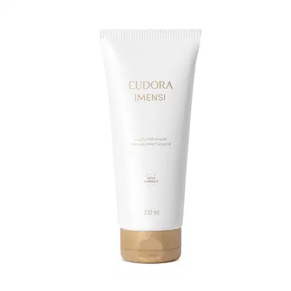 Embalagem tubular branca de plástico com detalhes em dourado. Rótulo com o nome do produto em letras douradas. Tampa dourada redonda na parte inferior da embalagem.