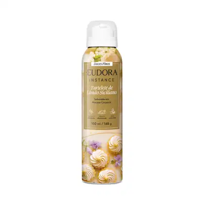 Embalagem em frasco plástico com tampa branca. Rótulo mostra merengues decorativos e flores lilás, no cento, um retângulo dourado com o nome Eudora Instance e detalhes do produto.150ml/148g. Propriedades hidratante, antioxidante e pele aveludada.