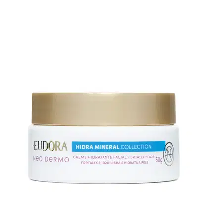 Embalagem tipo pote do Creme hidratante facial fortalecedor da linha Hidra Mineral da Eudora. Embalagem branca com tampa de rosquear dourada na parte superior, rótulo em tons de verde, vermelho e dourado no fundo branco.