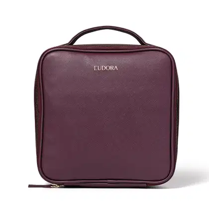 Nécessaire portátil da marca Eudora. Formato retangular com alça para transporte. Confeccionado em material sintético texturizado na cor vinho. Apresenta zíper ao redor para abertura e fechamento. O logotipo "Eudora" está estampado em letras douradas