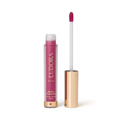 Batom Líquido Matte Supreme em embalagem transparente com tampa dourada e aplicador do tipo bastão. Produto com design minimalista e rótulo dourado no frasco.