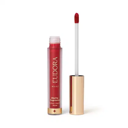Batom Líquido Matte Supreme em embalagem transparente com tampa dourada e aplicador do tipo bastão. Produto com design minimalista e rótulo dourado no frasco.