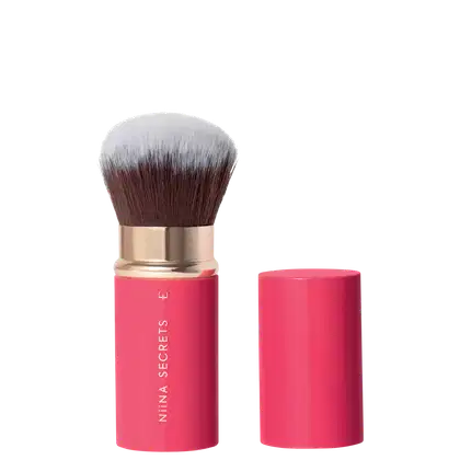 Pincel de maquiagem rosa com cabo dourado da marca Niina Secrets, acondicionado em embalagem cilíndrica rosa.