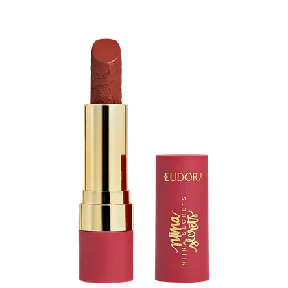Batom vermelho-alaranjado com relevo floral em embalagem dourada da marca Eudora.