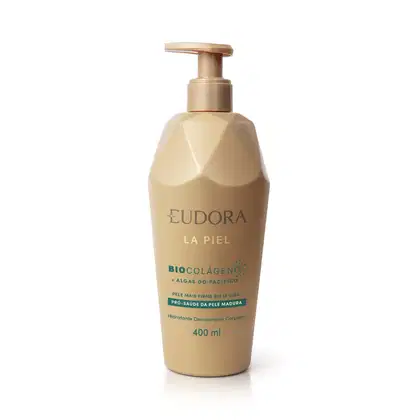 Embalagem plástica transparente em tom bege e dourado com bomba dosadora na parte superior. Rótulo com texto em verde. Design minimalista com nome da marca e linha em destaque em cor dourada mais brilhante que a da embalagem.