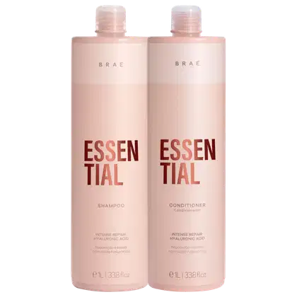 Dois frascos plásticos de shampoo e condicionador da marca Brae, na linha Essential. Os frascos têm formato cilíndrico e cor rosa claro. Na frente, está impresso "Essential" em letras marrons, abaixo do nome da marca Brae.