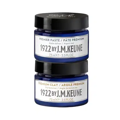 Dois frascos de produtos Keune, um de "Premier Paste" e outro de "Premium Clay", ambos com 75 ml e rótulos azuis com texto em branco.