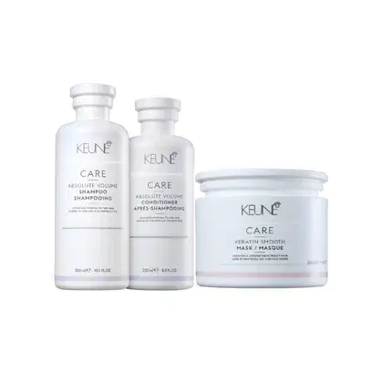 Três produtos da linha Keune Care: shampoo, condicionador e máscara para cabelos, em embalagens brancas com detalhes em cinza, exibindo o nome da marca e a linha "Absolute Volume" e "Keratin Smooth".