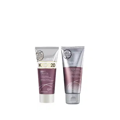 Dois produtos de tratamento capilar da marca Joico: um tubo de máscara "Defy Damage" e um tubo de máscara protetora "Defy Damage", ambos em embalagens prateadas e roxas com detalhes em branco.