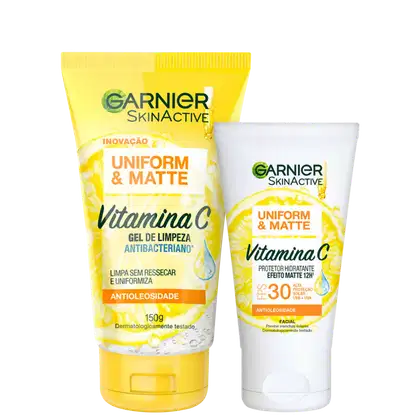 A imagem mostra dois produtos de skincare da linha Garnier Skinactive Uniform & Matte com Vitamina C: um gel de limpeza antibacteriano em tubo amarelo e um protetor hidratante matte com FPS 30 em pote branco.