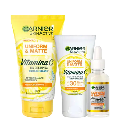 A imagem mostra três produtos de skincare da linha Garnier Skinactive Uniform & Matte com Vitamina C: um gel de limpeza antibacteriano em tubo amarelo, um protetor hidratante matte com FPS 30 em pote branco, e um sérum antioxidante em frasco transparente.