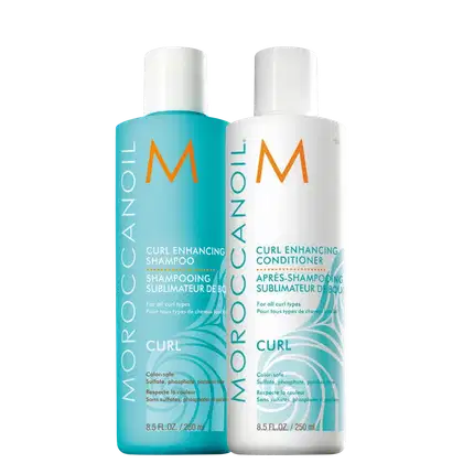 Dois frascos de produtos para cabelos cacheados da marca Moroccanoil. Um frasco azul turquesa contém shampoo, enquanto o frasco branco contém condicionador. Ambos os frascos têm 250ml e exibem o logotipo "M" laranja da marca,