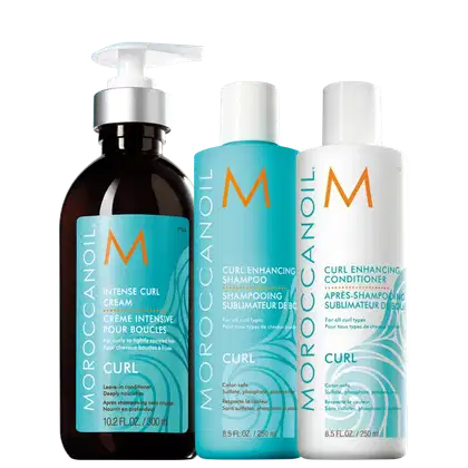 Produtos para cabelos cacheados da linha Moroccanoil Curl. Um creme intensivo de 300ml; um shampoo de 250ml e um um condicionador de 250ml. Todos os frascos exibem o logotipo "M" da marca Moroccanoil. As cores predominantes são turquesa, branco e laranja.