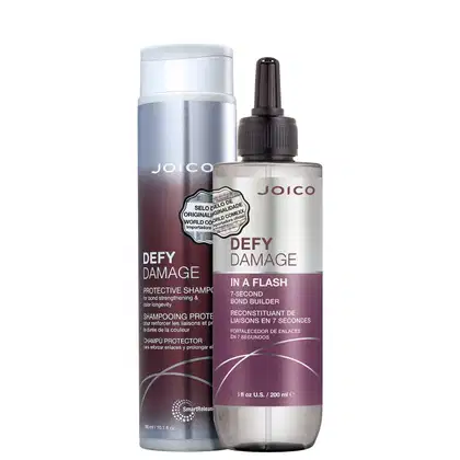 Produtos Joico Defy Damage: shampoo protetor em embalagem prateada e branca, e tratamento de reconstrução em frasco com rótulo roxo e branco, ambos com informações sobre fortalecimento e proteção da cor.