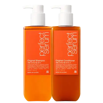 Dois frascos de plástico laranja com bombas brancas, contendo Shampoo Original e Condicionador Original da marca Mise en Scène. Os rótulos exibem informações sobre os ingredientes e a marca.