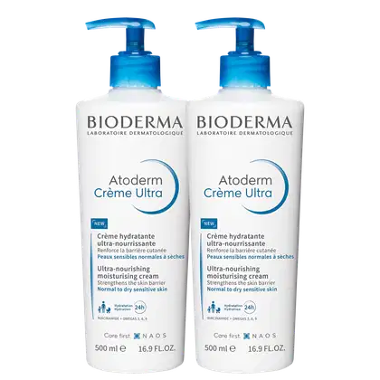 Dois frascos brancos com bombas doseadoras azuis da marca Bioderma, contendo o produto "Atoderm Crème Ultra",  de 500ml cada, um creme hidratante ultra-nutritivo para pele sensível normal a seca.