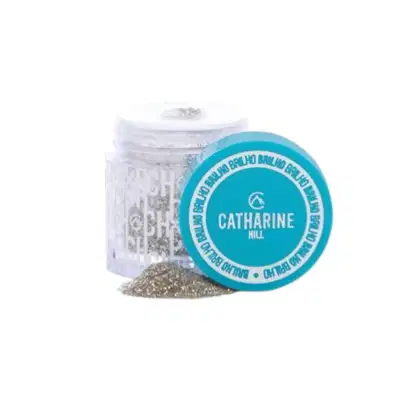 Frasco de vidro transparente contendo um produto em pó da marca Catharine Hill, com tampa azul turquesa e rótulo com o nome da marca em letras brancas.