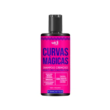 Frasco de shampoo cremoso hidro-reconstrutor da linha Curvas Mágicas da Widi Care, com embalagem rosa vibrante e detalhes em azul marinho. Contém óleos de rosa mosqueta, macadâmia e extrato de quinoa e açaí orgânico.