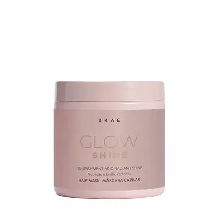 A imagem mostra a máscara capilar Glow Shine da marca Braé. Seu pote é rosa claro.