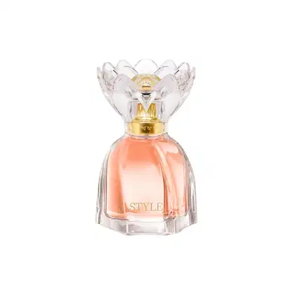 Frasco de perfume de cristal com tampa dourada em formato de flor, contendo líquido de cor salmão. Rótulo com a palavra "STYLE" em destaque.