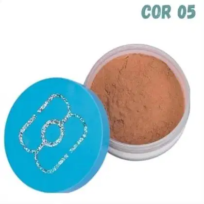 Pó compacto de maquiagem em embalagem plástica transparente. O pó tem uma tonalidade marrom terrosa. A tampa é azul turquesa e exibe um logotipo estilizado em glitter prateado.
