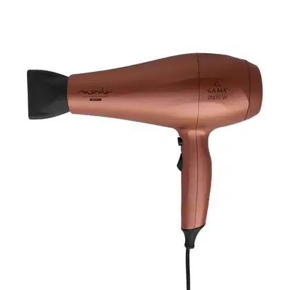 A imagem mostra o secador de cabelo da marca GA.MA Italy. Ele possui o corpo alongado na cor cobre metálico com detalhes pretos. Logotipo "Marula" e especificações "Gama 2000 W" impressos no corpo. Bico concentrador de ar removível na cor preta.