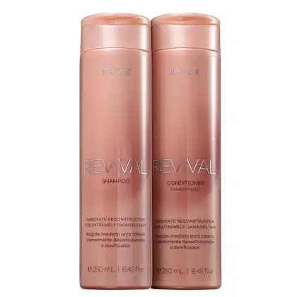 Dois frascos de plástico rígido na cor rosa metálico, contendo shampoo e condicionador da linha Revival da marca Brae. Os frascos têm formato cilíndrico e tampa rosqueável na mesma tonalidade.