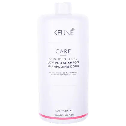 Frasco branco da linha Keune Care, com rótulo indicando "Confident Curl Low-Poo Shampoo", produto para cabelos cacheados, com informações sobre o tipo de cabelo e volume do produto.