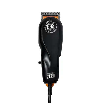 A imagem mostra uma máquina de cortar cabelo com corpo preto com detalhes em laranja. Possui uma lâmina aparadora visível e o logotipo "GBS Salon Exclusive" impresso na parte superior. Na parte inferior, está escrito "Absolute Zero.