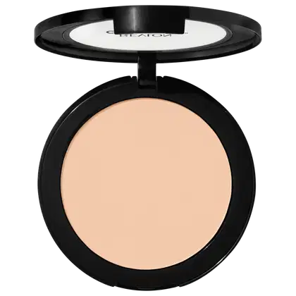 Pó compacto de maquiagem Revlon em embalagem redonda preta. A superfície do pó tem uma cor bege claro uniforme. A tampa transparente exibe o logotipo "Revlon" em letras brancas. O produto apresenta um design minimalista e elegante.