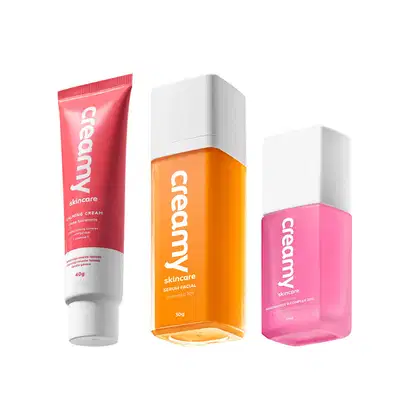 A imagem mostra uma bisnaga pequena de hidratante facial vermelha com detalhe e tampa branca, um frasco retangular transparente de sérum cor laranja e tampa branca e um frasco retangular transparente de sérum facial cor rosa e tampa branca.
