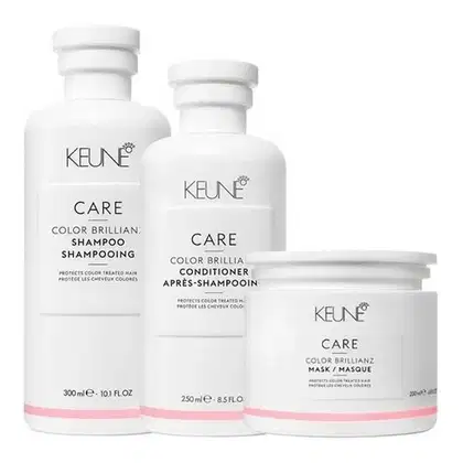 linha de cuidados para cabelos coloridos da marca Keune. Ela consiste em um shampoo, um condicionador e uma máscara, todos com a mesma embalagem branca e rosa.