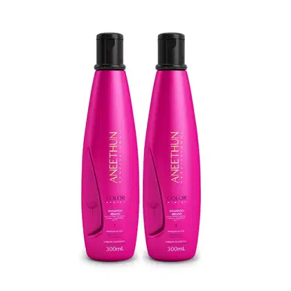 A imagem mostra dois frascos do shampoo da linha Color System de Aneethun. São cilíndricos na cor rosa vibrante com a tampa preta.