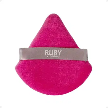 A imagem mostra uma esponja de maquiagem em formato triangular rosa, com uma fita cinza com logo da marca em branco.