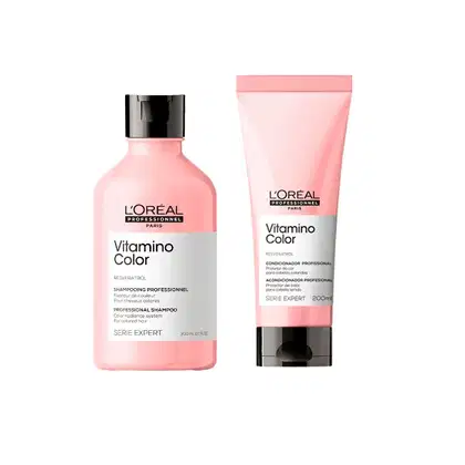 A imagem mostra dois produtos de cuidados capilares da linha Vitamino Color da L'Oréal Professionnel. Um é um shampoo em um frasco plástico rosa de 300ml e o outro é um condicionador em um tubo rosa de 200ml.