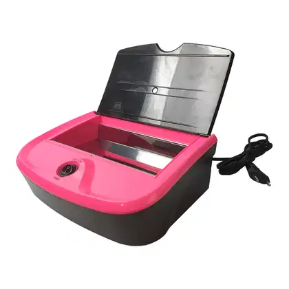 Estufa de Esterilização de Alicates. O produto tem uma caixa plástica rígida na cor rosa vibrante e preto. A parte superior é transparente com uma tampa articulada.
